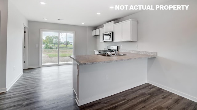 kitchen featuring kitchen peninsula, dark hardwood / wood-style flooring, stainless steel appliances, sink, and white cabinets