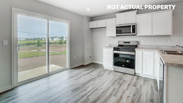 kitchen featuring white cabinetry, sink, appliances with stainless steel finishes, and light hardwood / wood-style flooring