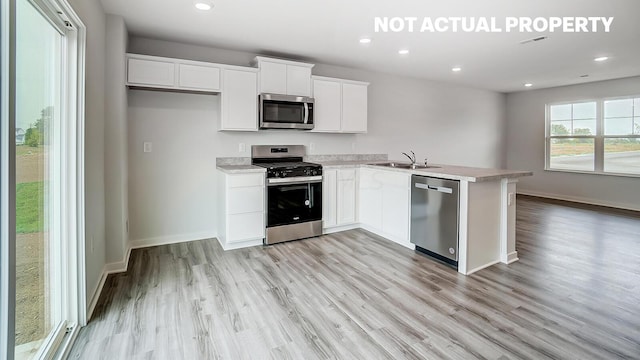 kitchen featuring sink, white cabinets, stainless steel appliances, and light wood-type flooring