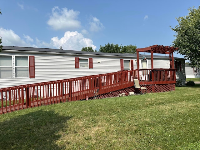 rear view of property with a pergola, a wooden deck, and a lawn