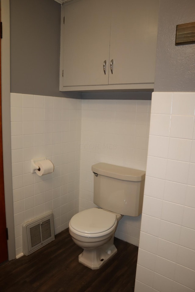 bathroom with hardwood / wood-style flooring, toilet, and tile walls