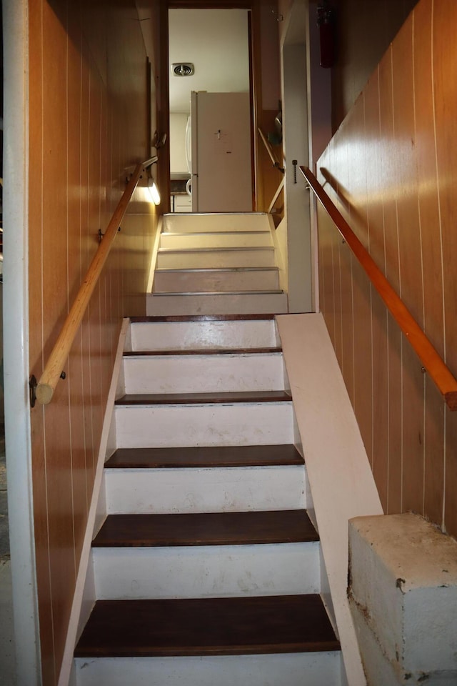 staircase featuring wood walls