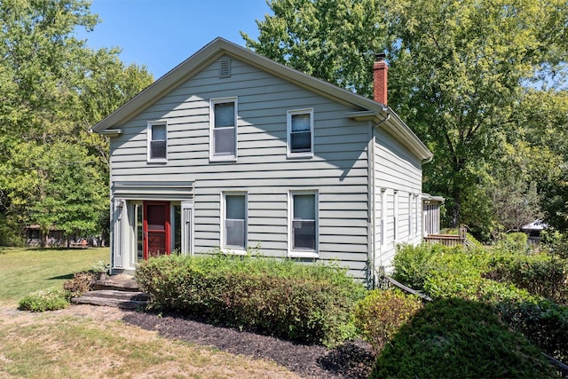 view of front of home featuring a chimney and a front lawn