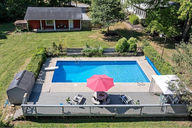 view of pool with a deck, an outdoor structure, fence, a yard, and a fenced in pool