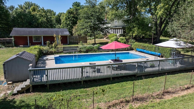 view of swimming pool featuring an outbuilding, a lawn, and a wooden deck