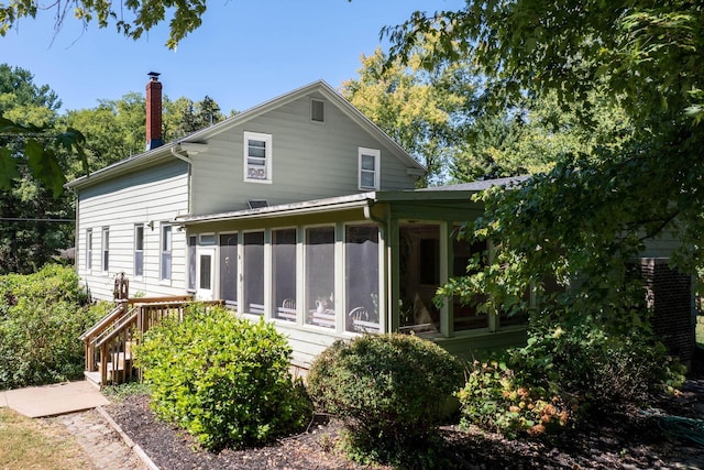 back of house featuring a sunroom and a chimney