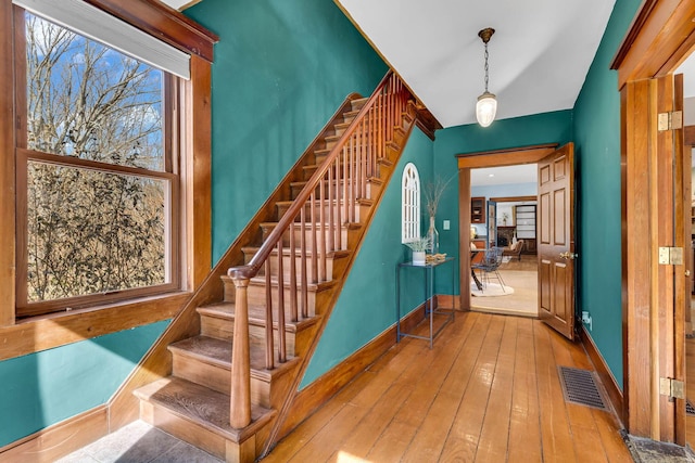 stairway with hardwood / wood-style flooring, baseboards, and visible vents