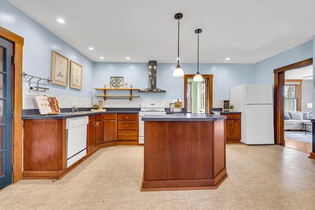 kitchen featuring white appliances, brown cabinetry, dark countertops, wall chimney range hood, and open shelves