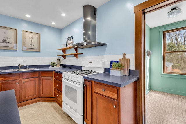 kitchen with white gas range oven, dark countertops, extractor fan, open shelves, and a sink