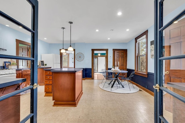 kitchen featuring a center island, decorative light fixtures, recessed lighting, brown cabinetry, and white appliances