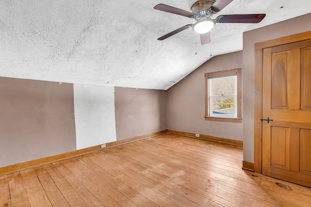 bonus room featuring lofted ceiling, ceiling fan, a textured ceiling, light wood-type flooring, and baseboards