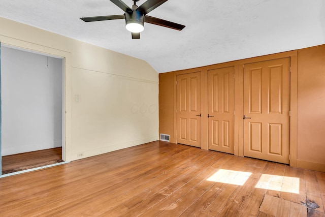 unfurnished bedroom featuring lofted ceiling, visible vents, light wood-style flooring, and baseboards