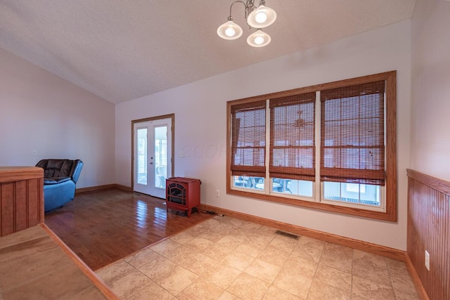 interior space featuring lofted ceiling, light wood-type flooring, a textured ceiling, and french doors