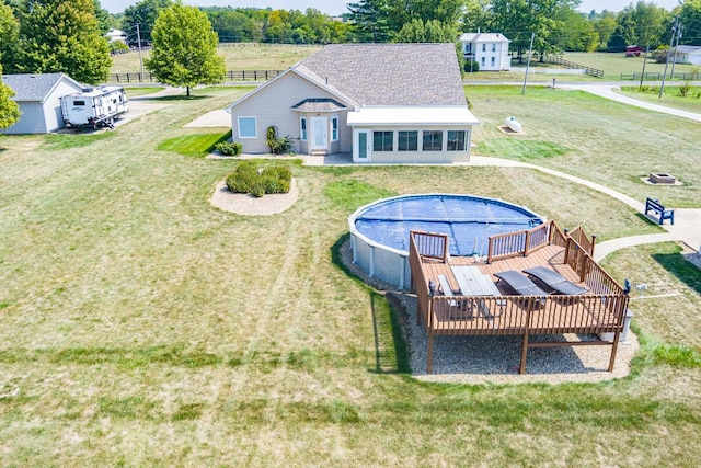 view of swimming pool with a sunroom, a wooden deck, and a lawn