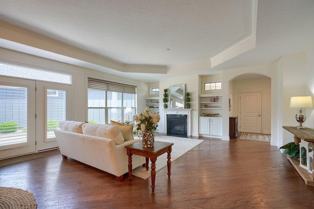 living room featuring dark hardwood / wood-style floors, a raised ceiling, and built in shelves