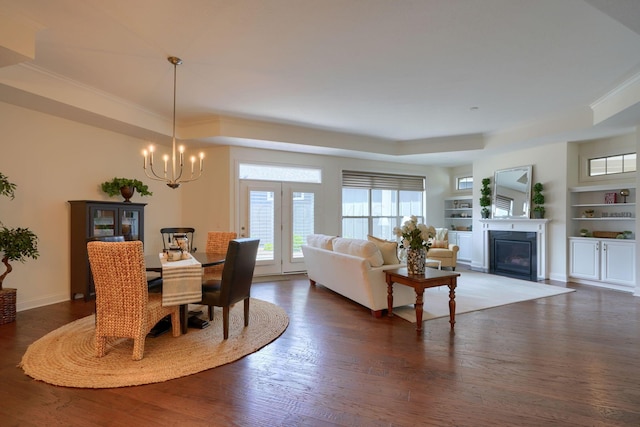 dining space featuring built in shelves, dark hardwood / wood-style floors, ornamental molding, and a notable chandelier