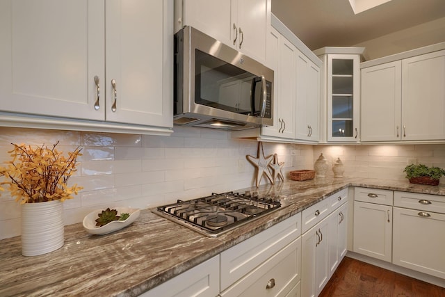 kitchen featuring backsplash, dark hardwood / wood-style floors, light stone countertops, white cabinetry, and stainless steel appliances