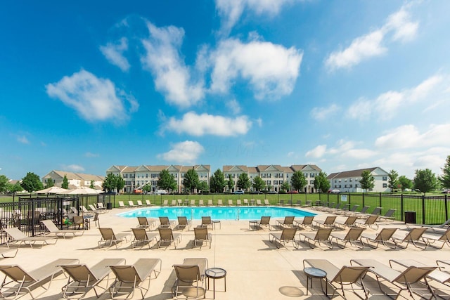 community pool featuring a patio area, a residential view, and fence