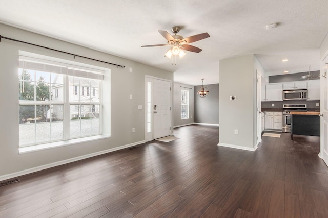 entryway featuring dark wood-style floors, visible vents, baseboards, and ceiling fan with notable chandelier