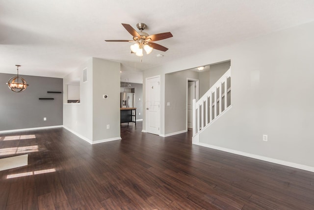 unfurnished living room featuring stairs, visible vents, dark wood-type flooring, baseboards, and ceiling fan with notable chandelier