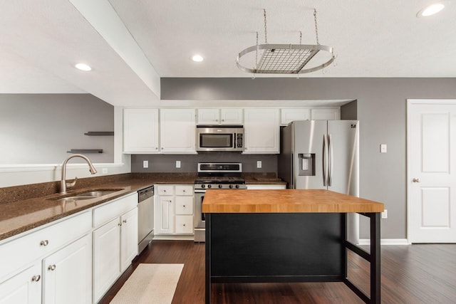 kitchen with white cabinets, appliances with stainless steel finishes, a sink, open shelves, and wooden counters