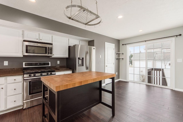 kitchen featuring dark wood-style floors, appliances with stainless steel finishes, white cabinets, butcher block countertops, and baseboards