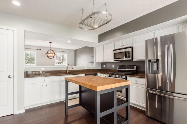 kitchen with dark wood-style flooring, stainless steel appliances, white cabinets, a sink, and wood counters