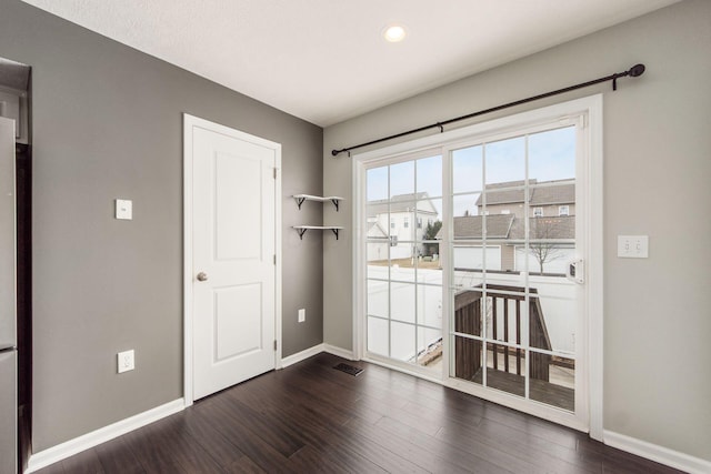 doorway featuring dark wood-style floors, visible vents, and baseboards