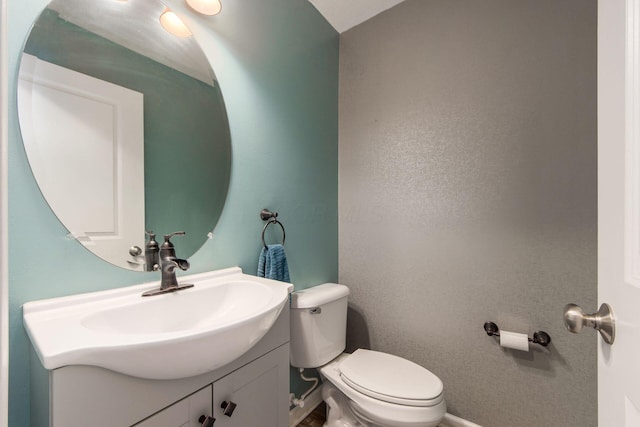 bathroom featuring baseboards, vanity, and toilet