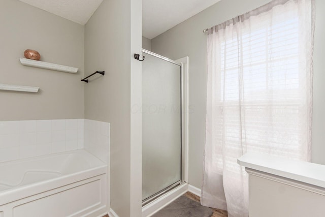 bathroom featuring a shower stall and a bath