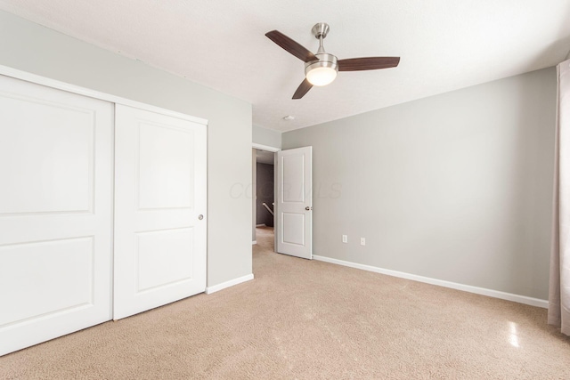 unfurnished bedroom featuring ceiling fan, baseboards, a closet, and light colored carpet