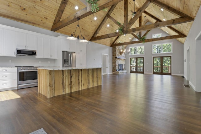 kitchen featuring white cabinets, a center island, stainless steel appliances, and dark wood-type flooring