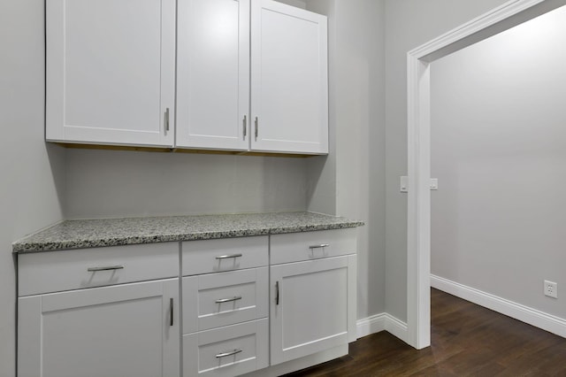 bar featuring white cabinetry, dark hardwood / wood-style flooring, and light stone counters