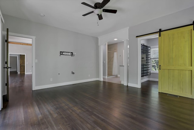 spare room featuring dark hardwood / wood-style floors, a barn door, and ceiling fan