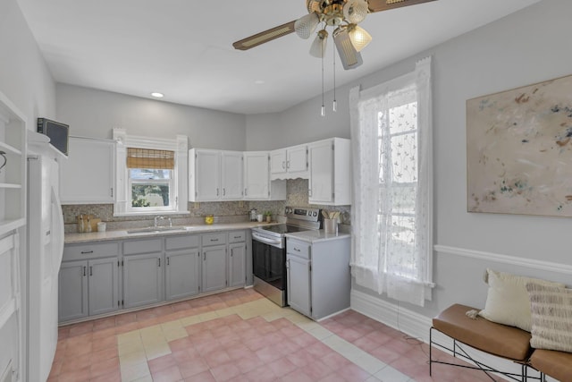 kitchen featuring decorative backsplash, ceiling fan, sink, gray cabinets, and stainless steel electric range oven