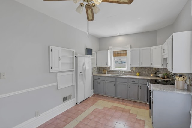 kitchen with gray cabinetry, sink, tasteful backsplash, white refrigerator with ice dispenser, and range