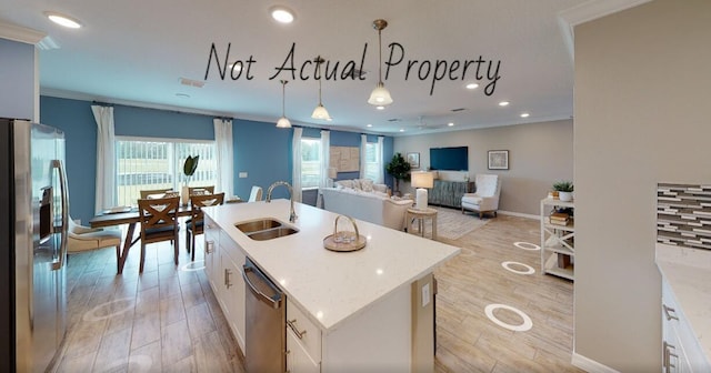 kitchen featuring white cabinets, appliances with stainless steel finishes, sink, and an island with sink