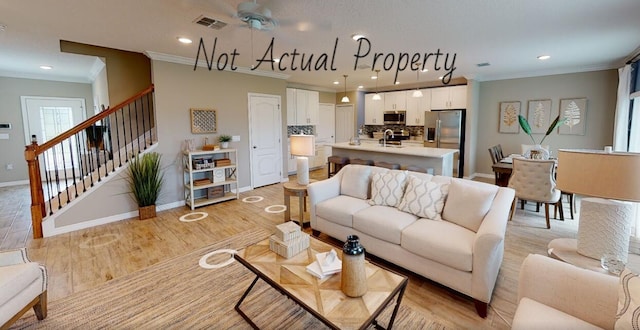 living room featuring light hardwood / wood-style flooring, ceiling fan, ornamental molding, and sink