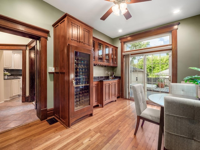 bar featuring decorative backsplash, ceiling fan, light hardwood / wood-style flooring, and beverage cooler