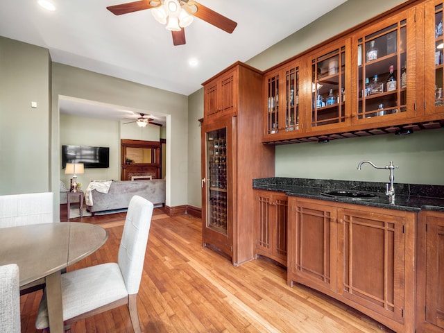 kitchen featuring dark stone counters, sink, wine cooler, light hardwood / wood-style flooring, and ceiling fan