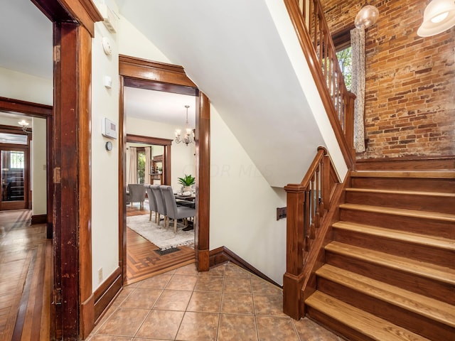 staircase featuring tile patterned floors, plenty of natural light, and a chandelier