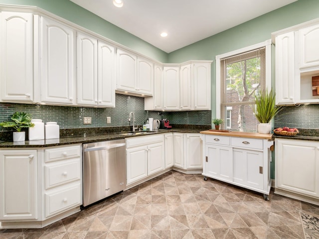 kitchen with dishwasher, sink, backsplash, dark stone counters, and white cabinets