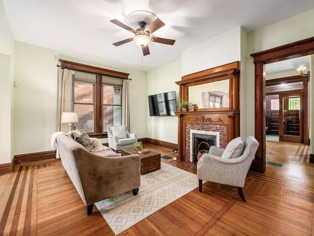 living room featuring ceiling fan and a brick fireplace