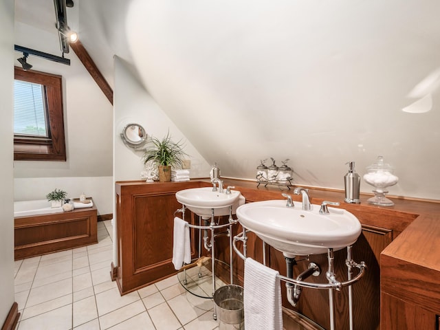 bathroom with tile patterned floors, a bathtub, dual sinks, and vaulted ceiling