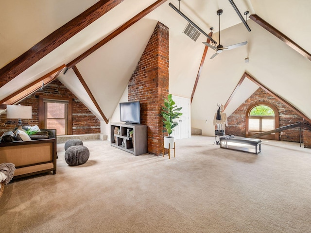 carpeted living room with ceiling fan, beamed ceiling, brick wall, and high vaulted ceiling