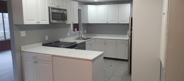 kitchen featuring kitchen peninsula, sink, white cabinets, and black appliances