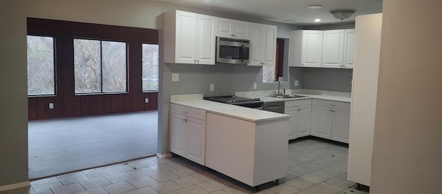 kitchen featuring wood walls, range, sink, light colored carpet, and white cabinetry