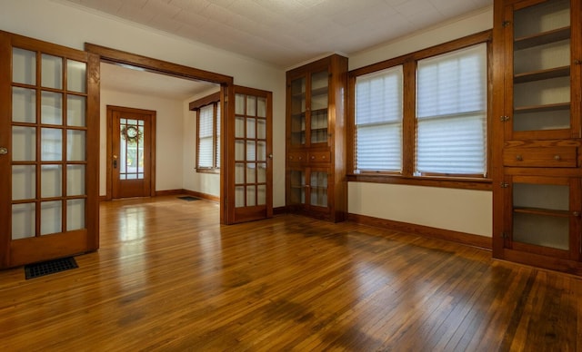 interior space with dark hardwood / wood-style flooring, crown molding, and french doors