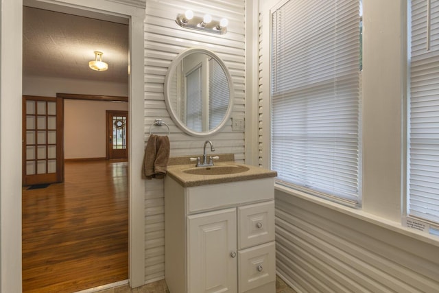 bathroom with a textured ceiling, vanity, hardwood / wood-style flooring, and wood walls