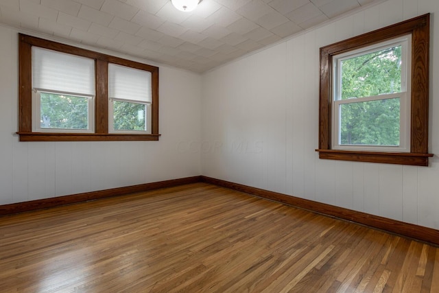 unfurnished room with wood-type flooring and wooden walls